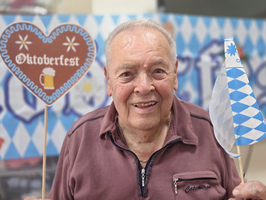 Ein älterer Mann hält Oktoberfest-Dekorationen in einer festlichen Umgebung.