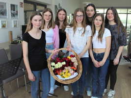 Eine Gruppe junger Frauen steht zusammen und hält einen Korb mit Rosen.