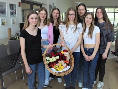 Eine Gruppe junger Frauen steht zusammen und hält einen Korb mit Rosen.