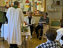 Ein Pastor spricht zu Gästen in einem Gemeinschaftsraum.