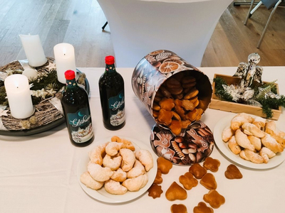 Weihnachtliche Leckereien: Kekse, Glühwein und Kerzen auf einem Tisch.