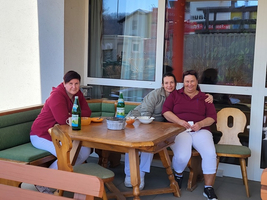 Drei Frauen sitzen entspannt an einem Tisch auf einer Terrasse.