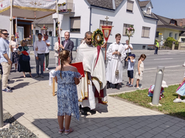 Eine religiöse Prozession mit Menschen und einem Priester in traditioneller Kleidung.