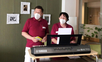 Zwei Personen mit Mundschutz singen vor einem Keyboard.