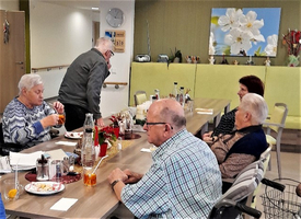 Ältere Menschen sitzen an einem Tisch und genießen ein gemeinsames Essen.