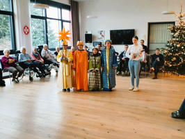 Kinder in Kostümen führen ein Weihnachtsstück vor Bewohnern eines Seniorenheims auf.