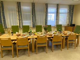 Ein gedeckter Tisch mit verschiedenen Speisen und Getränken, umgeben von Stühlen.