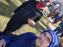 Ein Junge mit Spiderman-Maske steht neben einem älteren Mann im Rollstuhl.