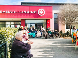 Ältere Menschen applaudieren bei einer Feier vor dem Samariterbund.