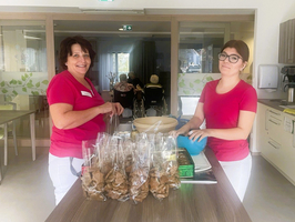 Zwei Frauen in roten T-Shirts bereiten Snacks in einer Küche vor.