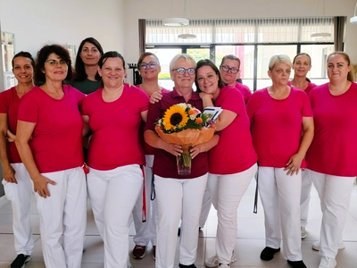 Eine Gruppe von Frauen in rosa T-Shirts hält Sonnenblumen in der Mitte.