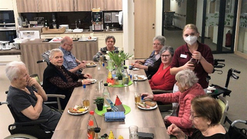 Eine Gruppe älterer Menschen genießt ein gemeinsames Essen im Essbereich.