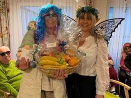 Zwei Frauen in Kostümen halten einen Korb mit Obst.