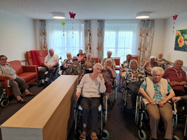 Eine Gruppe älterer Menschen in Rollstühlen sitzt in einem Gemeinschaftsraum.