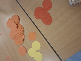 Stapelhaufen aus orangefarbenen und gelben Papierkreisen auf einem Tisch.