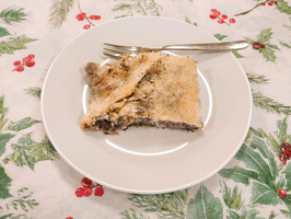 Ein Stück Kuchen auf einem weißen Teller mit Besteck daneben.