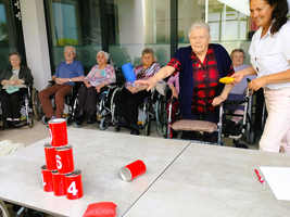 Ältere Frauen spielen ein Wurfspiel mit bunten Gegenständen.
