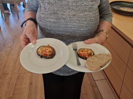 Eine ältere Frau hält zwei Teller mit Essen und einem Stück Brot.