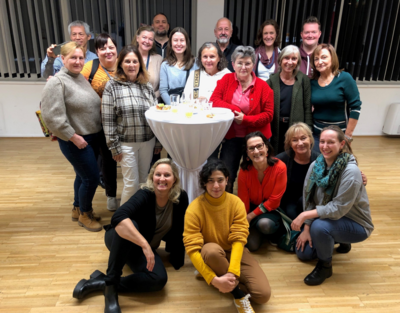 Gruppenbild Team Ehrenamt, mehrere Personen vor bzw. hinter einem Stehtisch, alle lächeln in Kamera