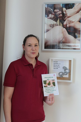 Eine Frau hält ein Plakat mit dem Thema Zusammenhalt in der Hand.