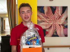 Junger Mann hält einen Geschenkkorb in einem freundlichen Raum.