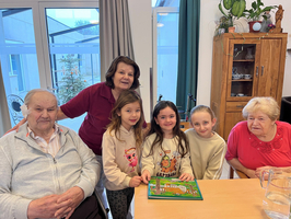 Eine Gruppe von fünf Personen, darunter zwei Kinder, posiert lächelnd mit einem Spiel.