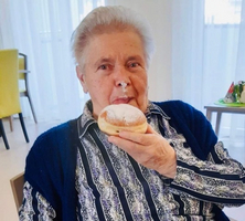 Eine ältere Frau hält einen Pudding-Brela in der Hand und lächelt.