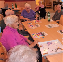 Senioren spielen gemeinsam ein Bingo-Spiel in einem gemütlichen Raum.