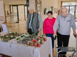 Drei Personen stehen an einem Tisch mit handgemachten Dekorationen.
