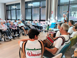 Eine Musikgruppe spielt für ein Publikum von Senioren im Rollstuhl.