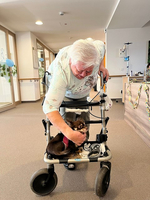 Eine ältere Frau mit Rollator, die einen kleinen Hund streichelt.