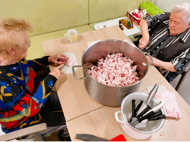 Älteres Paar bereitet gemeinsam Fleisch in einer großen Schüssel vor.