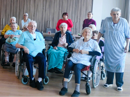 Eine Gruppe älterer Menschen in Rollstühlen, in einem hellen Raum versammelt.
