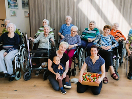 Gruppe von älteren Menschen im Rollstuhl mit zwei Frauen und einem Kind.