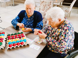 Zwei Frauen bemalen bunte Ostereier am Tisch.