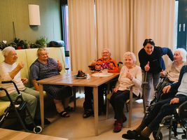 Eine Gruppe älterer Frauen und einer Betreuerin lächelt und zeigt Daumen hoch.