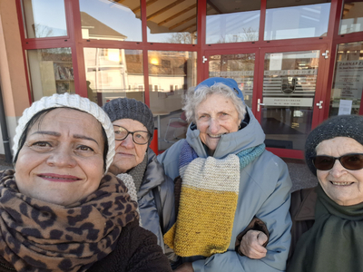 Eine Gruppe von vier Frauen posiert lächelnd vor einem Gebäude.