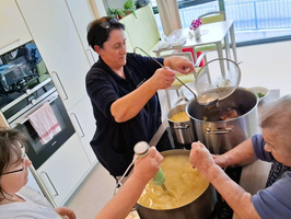 Drei Personen kochen gemeinsam in einer modernen Küche.