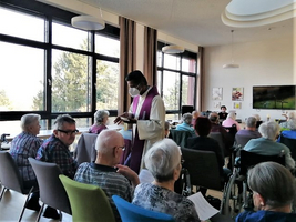 Ein Priester leitet eine Andacht vor einer Gruppe älterer Menschen.
