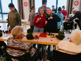 Jugendliche und Senioren basteln zusammen mit Weihnachtsdekoration.