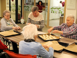 Ältere Frauen backen gemeinsam Plätzchen in einer freundlichen, hellen Umgebung.