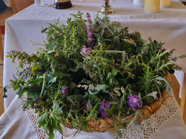 Ein Tisch mit Kräutern, einer Statue und Blumenarrangements.