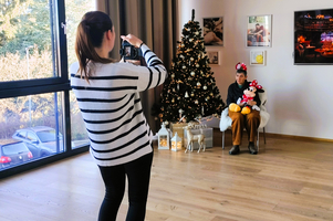 Eine Person sitzt vor einem Weihnachtsbaum und wird fotografiert.