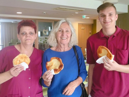 Drei Personen halten frisch gebackenes Brot in der Hand und lächeln.