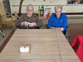 Zwei ältere Frauen sitzen an einem Tisch mit Bastelmaterialien.