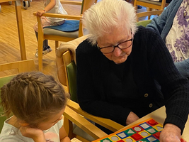 Eine ältere Frau spielt mit einem Mädchen ein Brettspiel.
