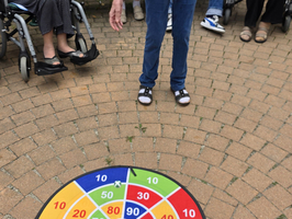 Eine Person steht über einem bunten Zielspielteppich im Freien.