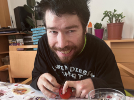 Ein Mann gestaltet bunte, natürliche Dekorationen aus Früchten und Samen.