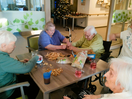 Ältere Menschen sitzen zusammen und genießen eine gesellige Runde mit Keksen und Getränken.