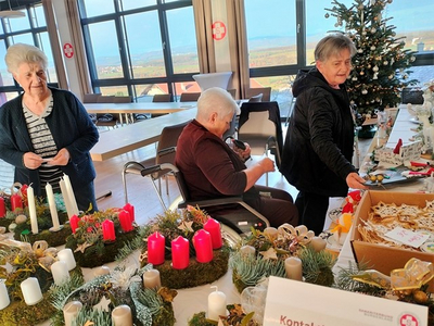 Drei Frauen dekorieren Adventskränze in einem festlich geschmückten Raum.